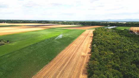 water spraying from irrigation system in agricultural field in marchfeld, austria - aerial drone shot