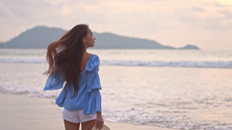 una joven mujer bonita caminando por la playa hacia el oleaje