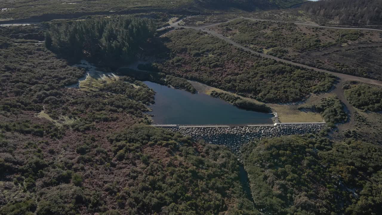 vista aérea de un pequeño depósito de agua que recoge la lluvia y lo dirige al depósito de aguas más grande en el valle