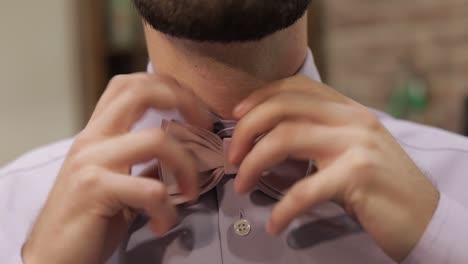 el novio ajusta la corbata de papilla en el fondo de la barbería. preparándose para ir a la novia