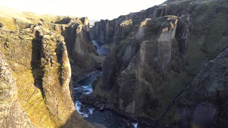 a rugged icelandic canyon with a river flowing through moss-covered cliffs