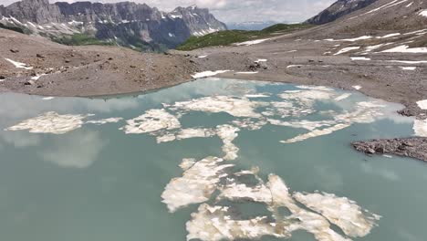 drone advancing over a clear-water lake in the swiss alps near urner-boden, a village located on the uri side of the klausen pass