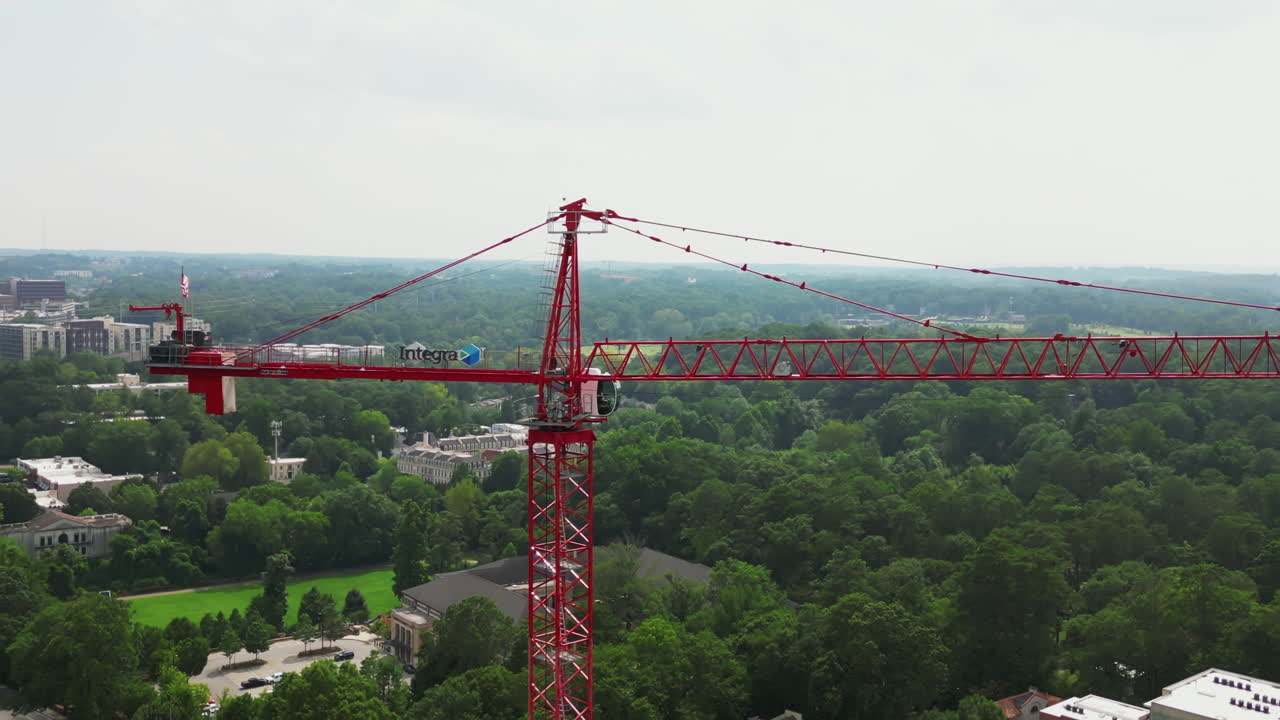Pull back shot of tall red tower crane on construction site in city