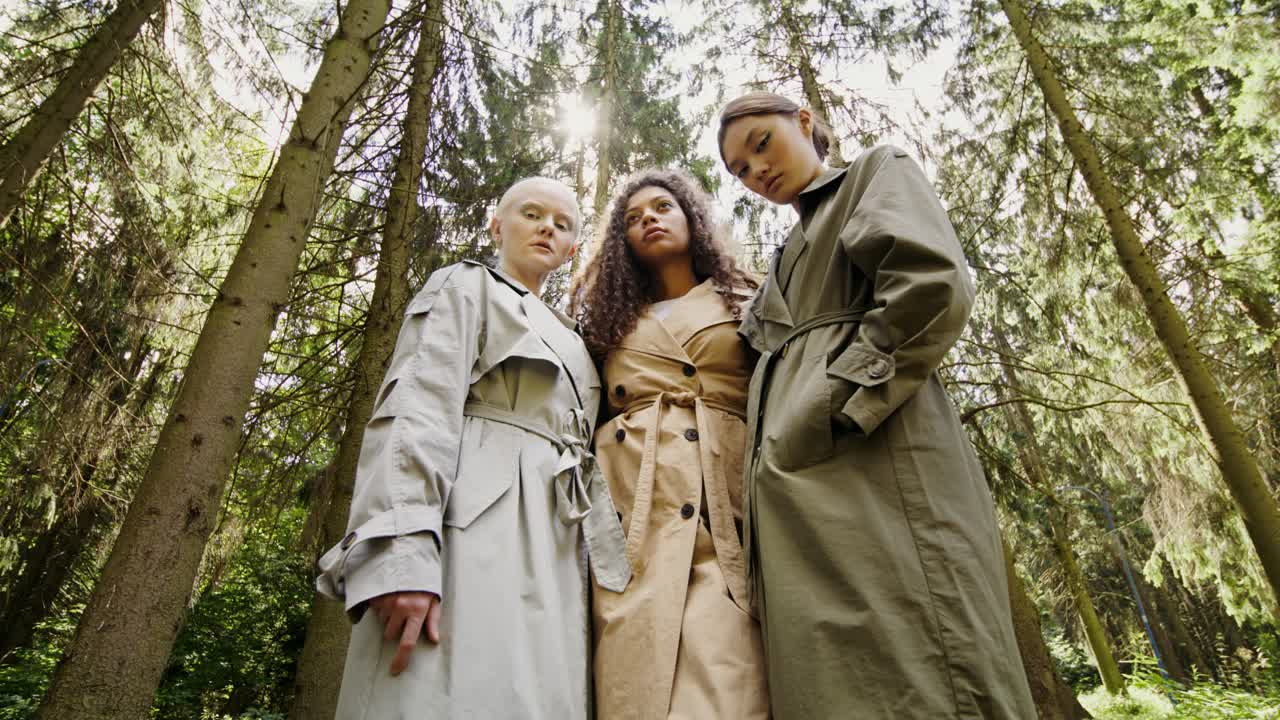 Three Women in Trench Coats in a Forest