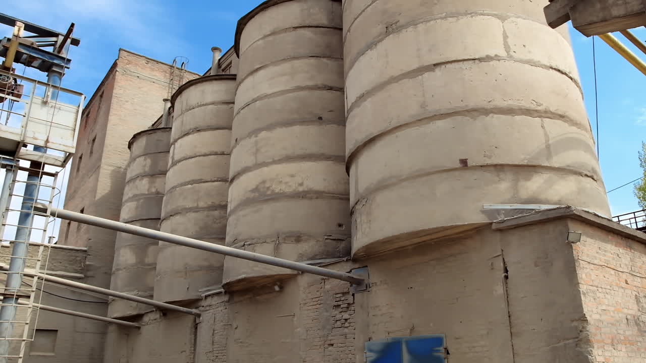 Huge industrial reservoir towers. Wide shot of cement storage on concrete factory. Exterior of industrial manufacturing. Close-up.
