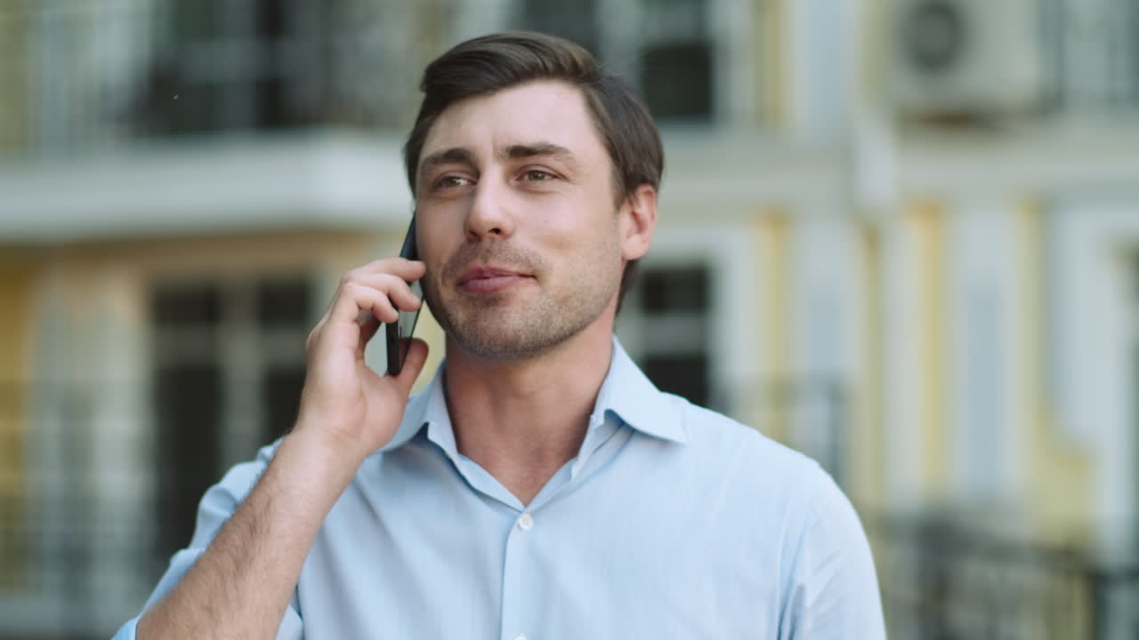 밖에서 셔츠를 입고 전화를 하는 사업가