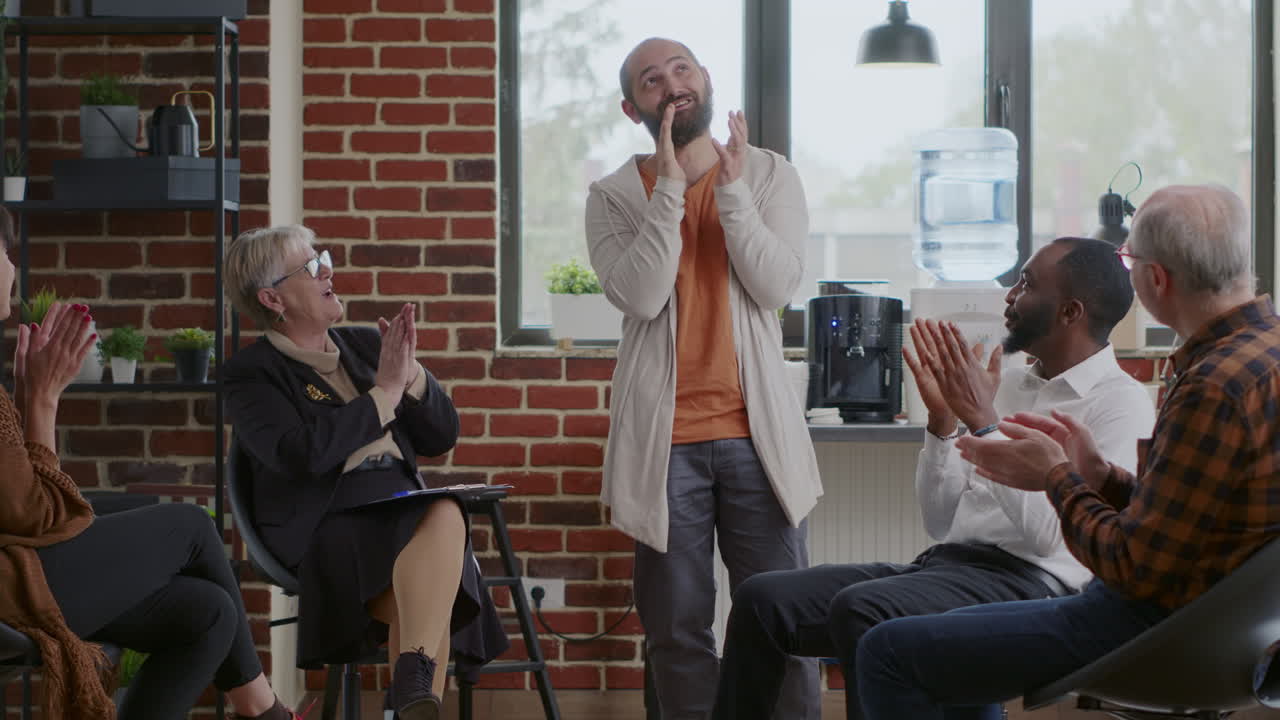 Happy man sharing therapy progress with group of people at aa meeting, celebrating together