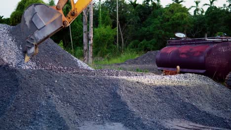 Backhoe-shovel-stacking-gravel-in-terrain