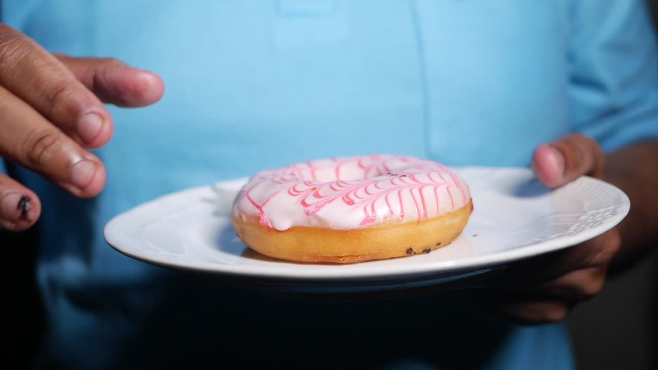 Persona che tiene una ciambella glassata su un piatto