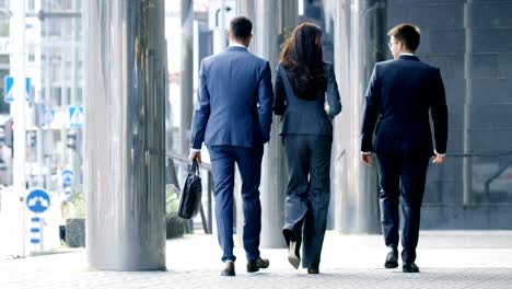 back view of three business people walking in the central business district.