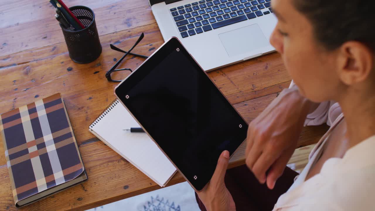 Mujer caucásica usando una tablet digital, trabajando desde casa
