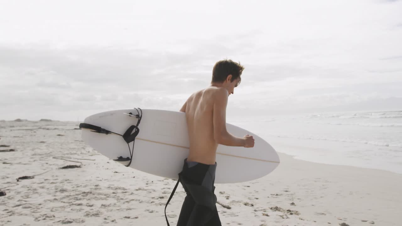 hombre joven en la playa con tabla de surf