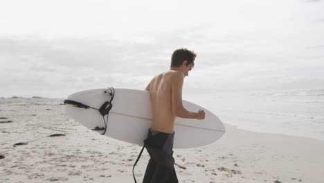 young man on beach with surfboard