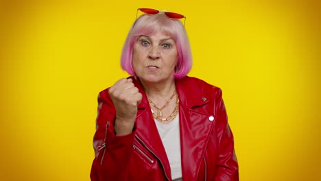 agresiva, enojada, abuela mayor, mujer tratando de pelear ante la cámara, sacudiendo el puño, boxeo, castigo.