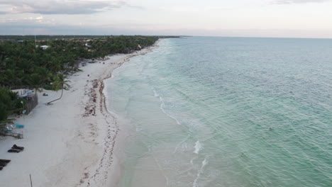 Luftaufnahme-Rollender-Wellen-In-Einem-Kristallklaren-Blauen-Meer-Mit-Weißem-Sandstrand