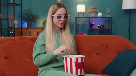 Una-Mujer-Joven-Sentada-En-Un-Sofá-Comiendo-Palomitas-De-Maíz-Y-Viendo-Un-Interesante-Juego-Deportivo-En-Serie-De-Televisión-En-Línea-En-Casa