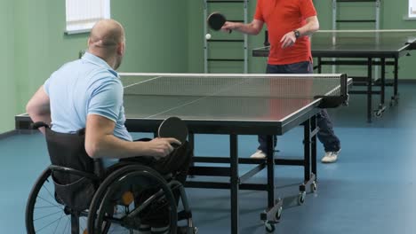 a man in a wheelchair plays ping pong. people with disabilities play table tennis. rehabilitation of the disabled. sport.