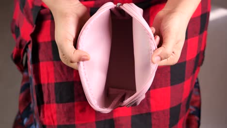 empty pink makeup pouch held in hands