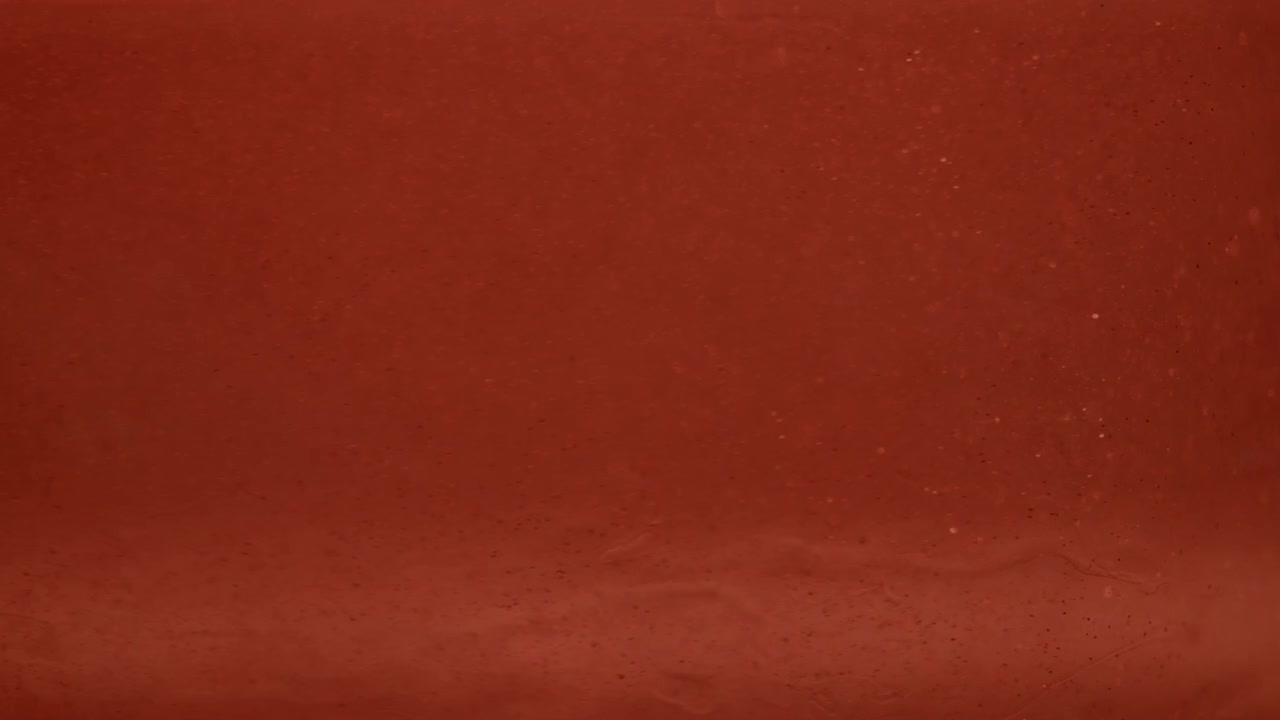 Texture liquida arancione liscia che si muove in uno sfondo astratto macro al rallentatore, vortica e gira in una sostanza gelatinosa