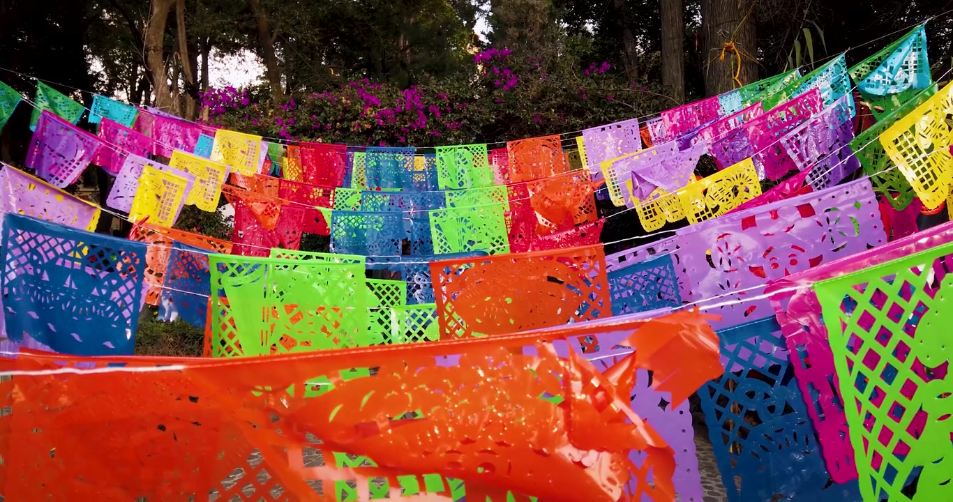 Tomada estática de papel picado como elemento decorativo da oferenda municipal durante as festividades do Dia dos Mortos no México.