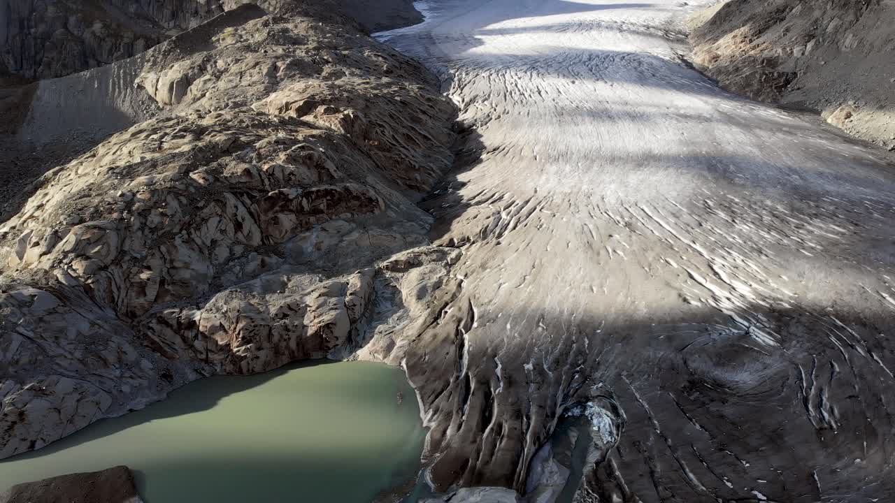 vista aérea del glaciar del ródano cerca del paso de montaña de furka en la frontera de valais y uri en suiza con una bandeja desde el hielo hasta el lago glacial lleno de icebergs