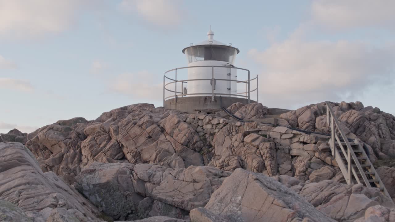 석양의 배경에 푸른 하늘과 구름이 있는 절벽 꼭대기에 있는 등대