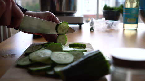 Man-chef-cutting-cucumber-on-chopping-wooden-board