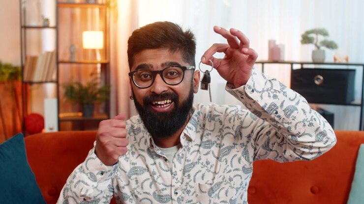 Indian man showing keys to new apartment celebrating real estate investment recommending purchase