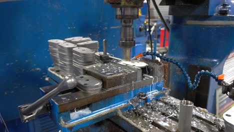 trabajador perforando metal con un taladro de banco en un entorno de fábrica
