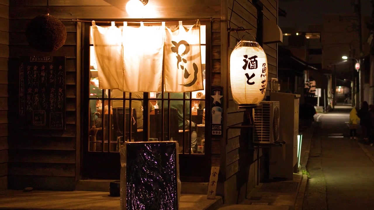 Una lenta panoramica rivela un accogliente ingresso di izakaya con lanterne in un vicolo buio