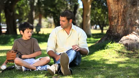 padre hablando con su hijo sentado en la hierba