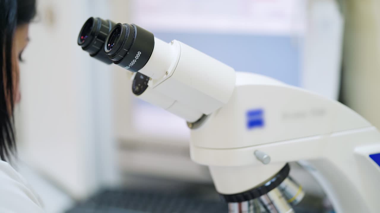Woman studying samples through the microscope. Young laboratory worker doing diagnostic with new device in clinic. Modern equipment in lab. Close-up.