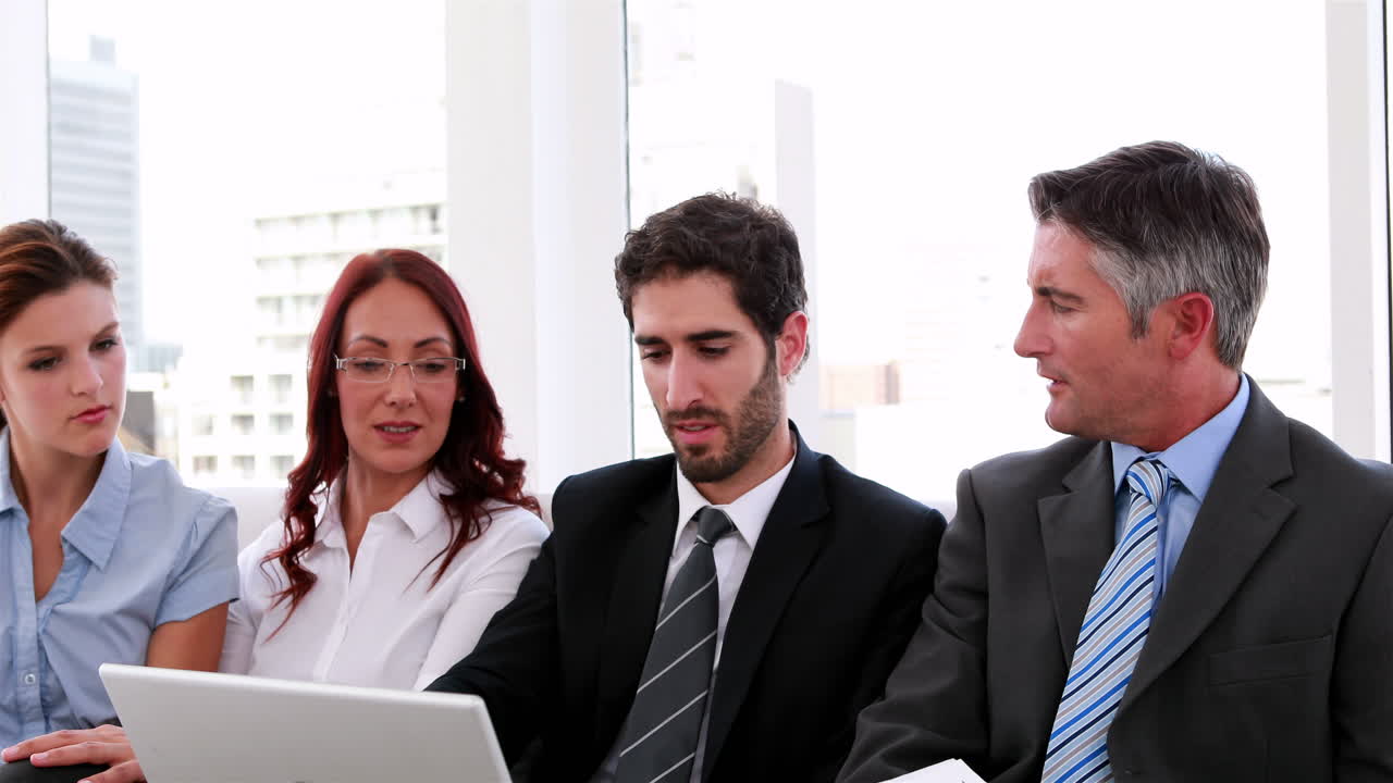 equipo de negocios sentado en el sofá teniendo una reunión usando una computadora portátil