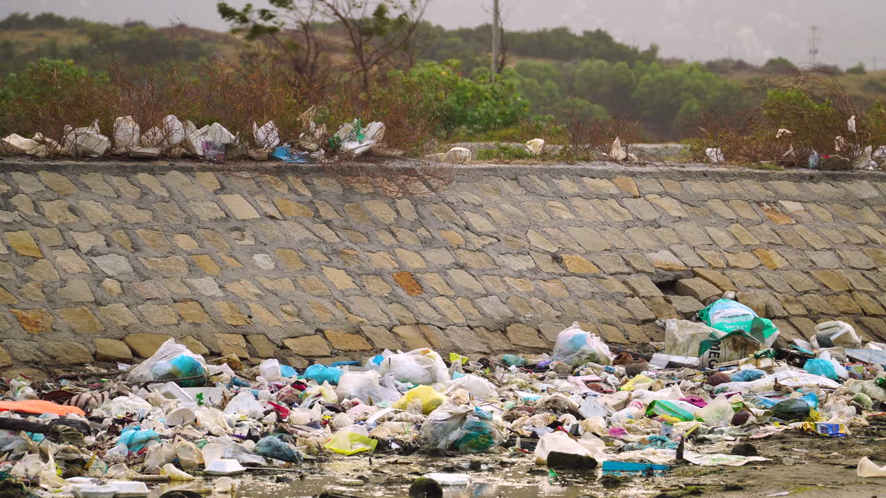 Dirty pollution plastic trash dumped on dry river wall in third world developing country