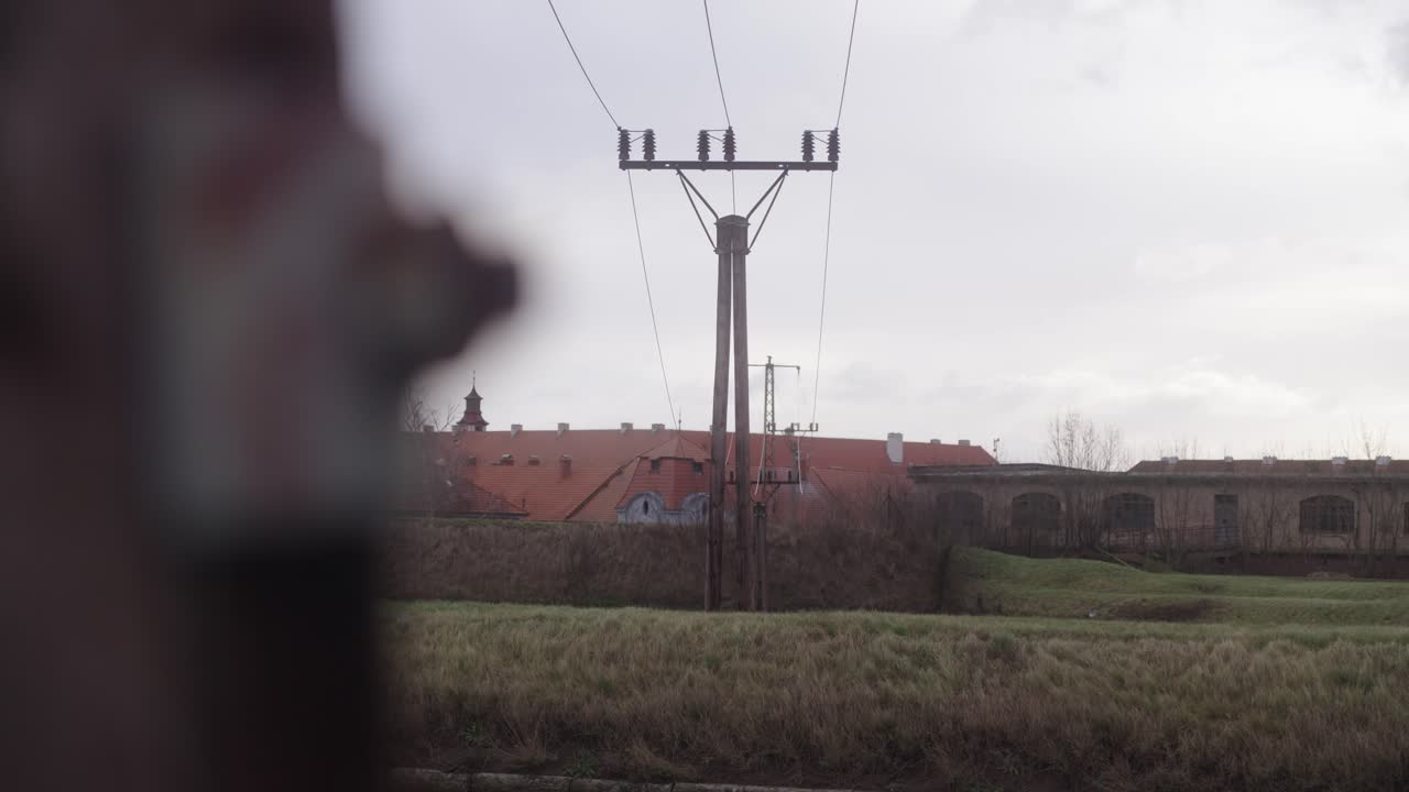 A close-up of a bolt in a wooden electric pole transitions to a wide shot of the Terez&iacute;n Fortress