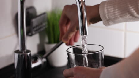 person filling glass with water