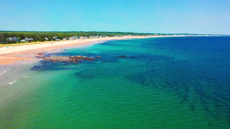 aerial drone flying above crowded beaches in saco, maine. peak-season fun with people sunbathing, vacation homes lining the sand, and atlantic waves hitting the lively east coast shoreline.