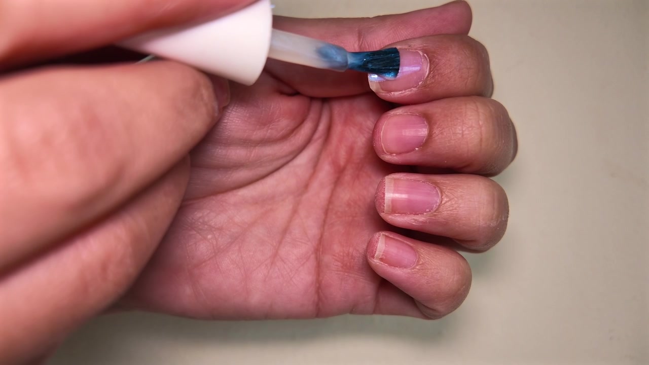 Nærbillede af en manicure-scene med en kvinde, der påfører neglelak under en selvforkælelses-skønhedssession