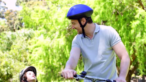 Padre-E-Hijo-Pequeño-En-Un-Paseo-En-Bicicleta-Por-El-Parque-Juntos