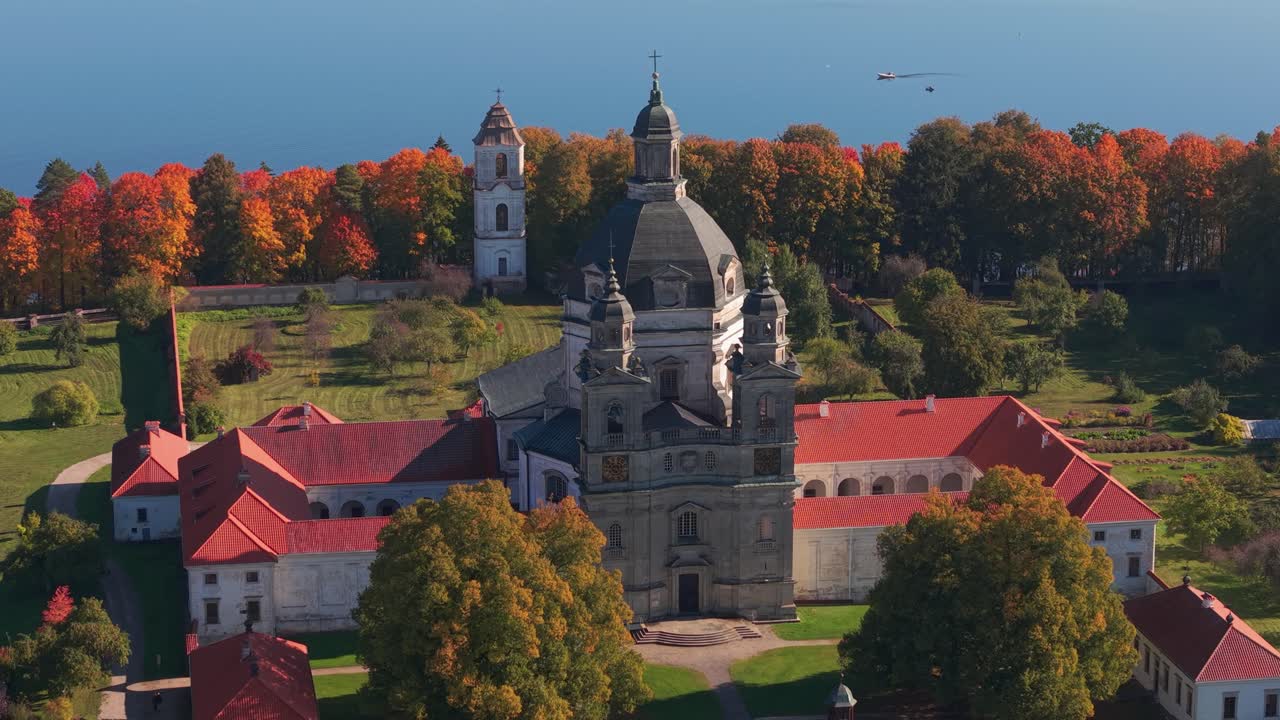 Aerial view of Pažaislis Monastery in Kaunas, Lithuania, surrounded by vibrant autumn trees near the Kaunas Reservoir. A stunning example of Baroque architecture and cultural heritage