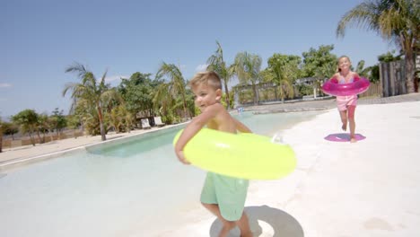 Glückliche-Kaukasische-Geschwister,-Die-Mit-Schlauchbooten-Am-Strandhaus-Laufen