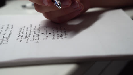 close up of a pen writing poem on white paper