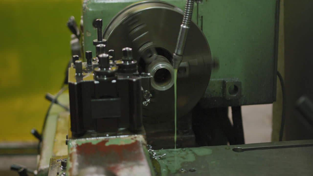Piece of machinery in the workshop at a factory turning and cutting a piece of metal pipe