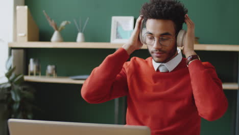 un joven escuchando música en su escritorio.