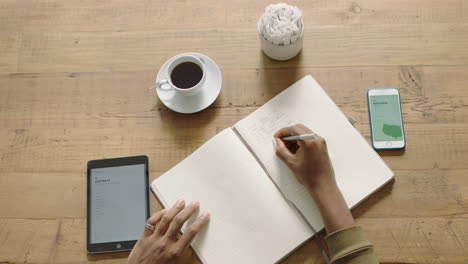 mujer de negocios joven manos escribiendo ideas de lluvia de ideas para proyectos haciendo notas trabajando en un café relajado usando tecnología móvil de cerca