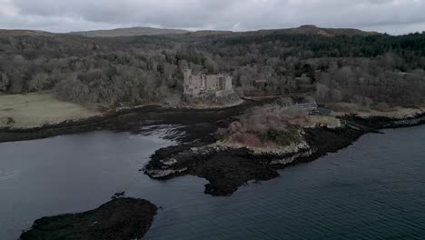 Castillo-De-Dunvegan-En-La-Isla-De-Skye,-Rodeado-De-Bosques-Y-Aguas-Costeras,-Bajo-Un-Cielo-Nublado,-Vista-Aérea