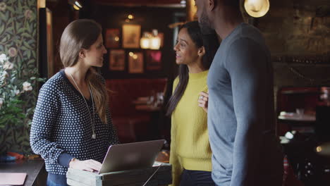 receptionist handing guest couple key as they check into hotel