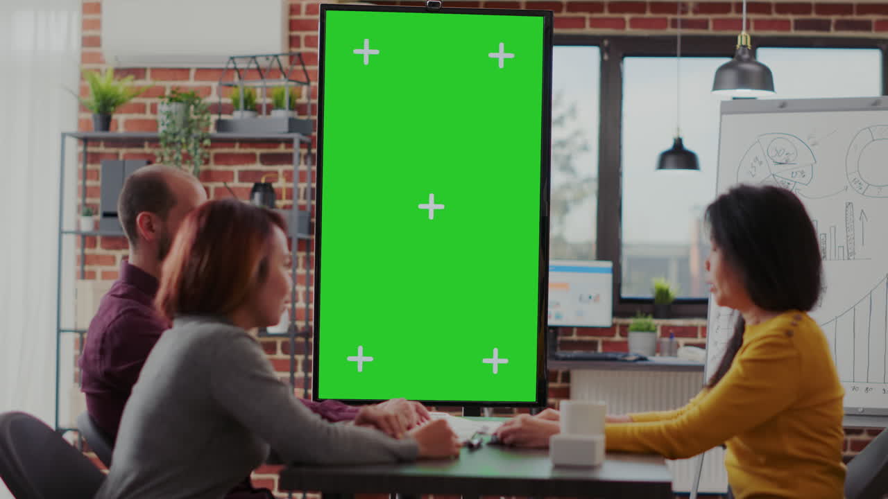 Coworkers meeting in office with green screen on monitor vertically