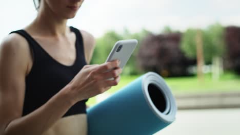 Video-of-woman-with-mobile-phone-walking-in-training-clothes