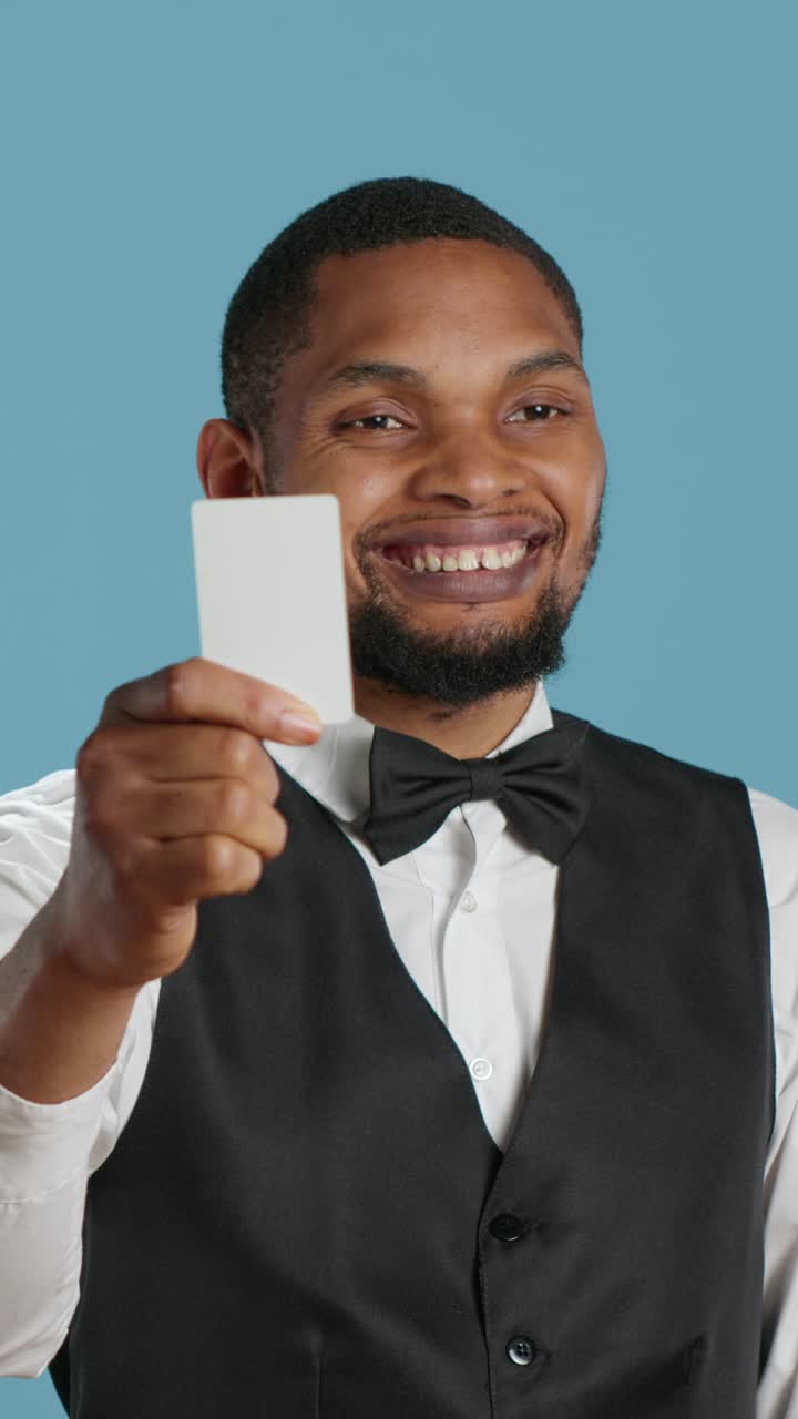 Uomo afroamericano sorridente in abito formale che tiene in mano un cartoncino bianco